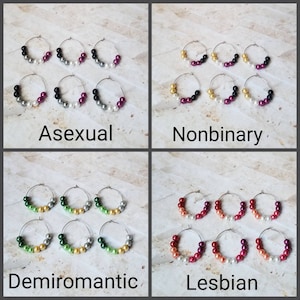 Op de afbeelding: Vier paar creolen met verschillende gekleurde kralen. De kralen zijn gerangschikt in een patroon dat verschillende seksuele oriëntaties vertegenwoordigt. De sets zijn gelabeld met "Aseksueel", "Non-binair", "Demiroamtisch" en "Lesbisch".