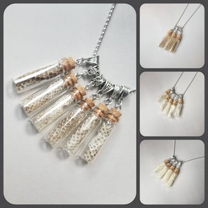 May include: A silver chain necklace with six small glass vials filled with snake skin. The vials are attached to the chain with silver clasps.