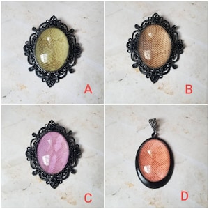 Può includere: Quattro diverse spille in metallo nero con motivi decorativi a filigrana. Ogni spilla presenta un cabochon rotondo in vetro con un motivo diverso. I cabochon sono in tonalità di rosa, beige e marrone chiaro.