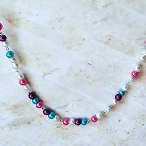 Könnte beinhalten: Eine silberne Kettenkette mit weißen, rosa, lila und türkisfarbenen Perlen.