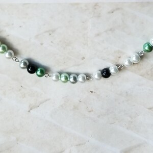 Peut inclure: Un collier en chaîne argent avec des perles blanches, vertes et noires.