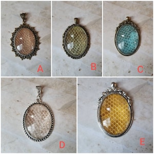 May include: Five oval-shaped pendants with different patterns. Each pendant has a metal frame and a glass insert with a unique design. The pendants are labeled A through E.