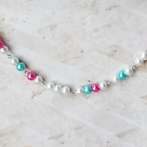 Könnte beinhalten: Eine silberne Kettenkette mit weißen, rosa und türkisfarbenen Perlen.