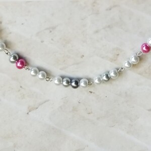 Könnte beinhalten: Eine silberne Kettenkette mit weißen, grauen und rosa Perlen.