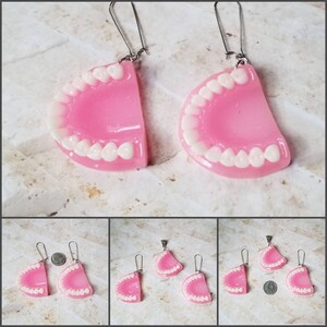 May include: A set of three pink and white plastic dentures, two are earrings and one is a pendant. The earrings have silver hooks and the pendant has a silver bail.