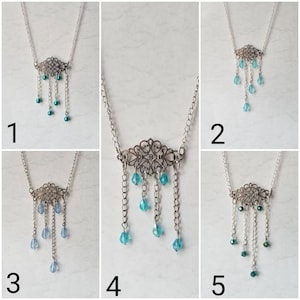 May include: Five silver necklaces with a filigree pendant and dangling turquoise blue beads. The necklaces are displayed on a white background.