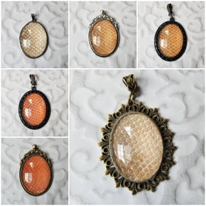 Pode incluir: Cinco pingentes diferentes com molduras de metal ornamentadas e inserções de vidro ovais que apresentam um padrão de pele de cobra bege.