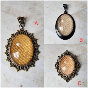 May include: Three pendants with a gold-toned metal frame and a clear oval-shaped resin insert with a beige snakeskin pattern.