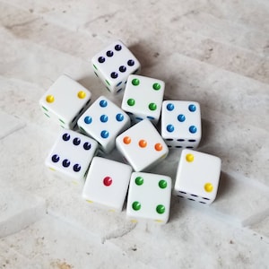May include: A group of ten white dice with colorful dots. The dice are arranged in a pyramid shape. The dice are all different colors, including red, blue, green, yellow, and orange.