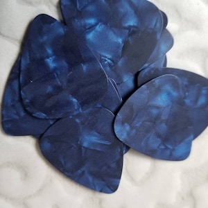 Könnte beinhalten: Ein Stapel blauer Gitarrenplektren mit Marmormuster.