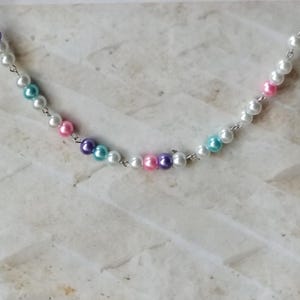May include: A silver chain necklace with white, pink, purple, and turquoise pearl beads.