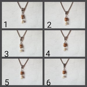 May include: Six silver necklaces with small glass vials filled with white crystals on a white background. Each necklace has a different length.