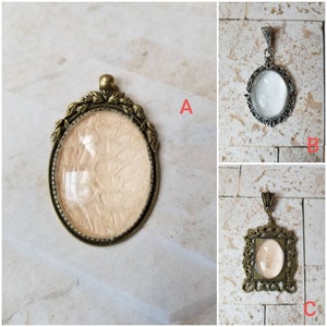 May include: Three antique-style pendant charms with clear glass oval and square inserts. The charms are made of metal with an aged bronze finish. The oval charms have a decorative floral design around the glass insert. The square charm has a decorative scroll design around the glass insert.