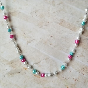 Könnte beinhalten: Eine silberne Kettenkette mit weißen, rosa und türkisfarbenen Perlen.