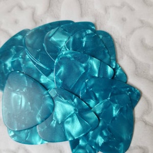 May include: A stack of teal guitar picks with a marbled pattern.