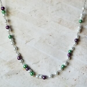 Könnte beinhalten: Eine silberne Kettenkette mit weißen, grünen und violetten Perlen.