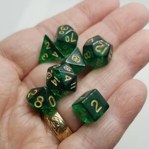 May include: A set of green dice with gold numbers. The dice are in a variety of shapes, including a d4, d6, d8, d10, d12, and d20.