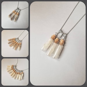 May include: A silver chain necklace with three small glass vials containing coiled snake skin. The vials have cork stoppers and are attached to the chain with silver clasps.