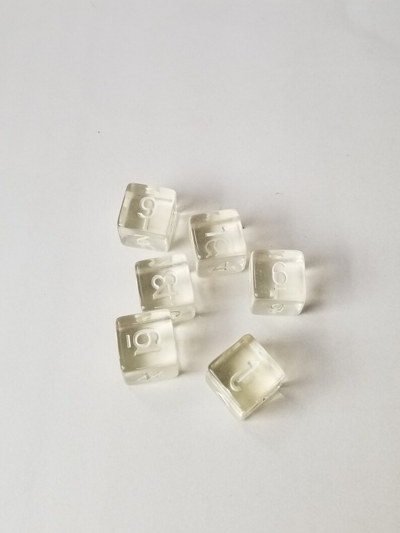 May include: Six clear plastic dice with white numbers on each side. The numbers are 1, 2, 3, 4, 5, and 6.