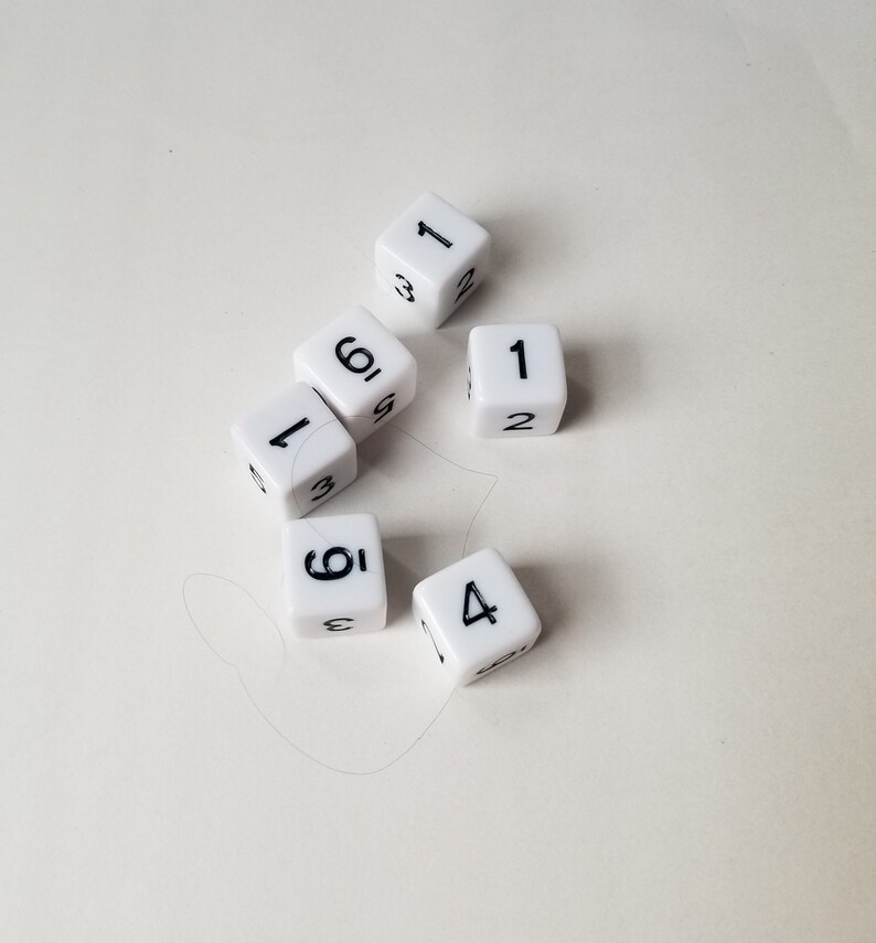 May include: Six white dice with black numbers. The dice show the numbers 1, 2, 3, 4, 5, and 6.