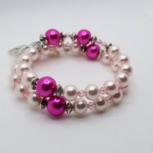 K&ouml;nnte beinhalten: Ein Armband mit zwei Reihen aus rosa und wei&szlig;en Perlen. Das Armband besteht aus rosa und silbernen Perlen mit einem silbernen Anh&auml;nger.