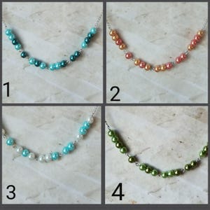 Puede incluir: Cuatro collares con cuentas de diferentes colores. Los collares están hechos con cuentas pequeñas y redondas en tonos de azul, verde, blanco y naranja. Las cuentas están enhebradas en una cadena plateada.