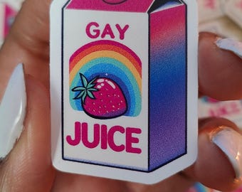 May include: A white carton with a pink, blue, and purple ombre design. The carton has a rainbow and a strawberry on the front and the words "GAY JUICE" in pink letters.