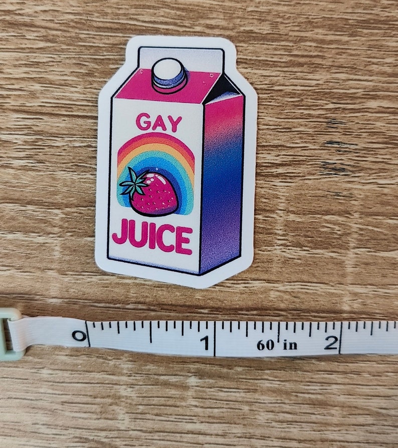 Puede incluir: Una pegatina de una caja de zumo gay con un arco&iacute;ris y una fresa en la parte delantera. La caja es rosa, azul y morada.