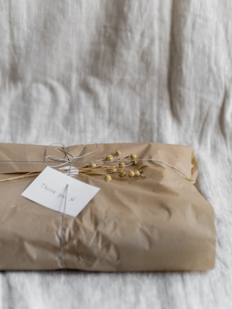May include: A brown paper gift bag tied with twine and decorated with dried flowers. A white card with the text "Thank you" is attached to the bag.