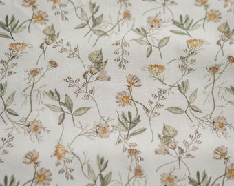 May include: A white fabric with a delicate floral pattern featuring small, light brown and yellow flowers and green leaves.