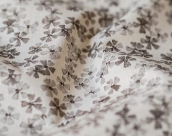 May include: White fabric with a subtle pattern of small, dark gray flowers.