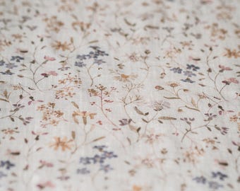 May include: A white fabric with a delicate floral pattern in shades of brown, pink, and blue. The fabric has a subtle linen texture.
