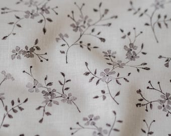 May include: A close-up of a white fabric with a delicate floral pattern in shades of gray. The fabric has a subtle texture and a soft, natural feel.