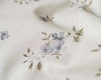 May include: White fabric with a delicate floral pattern featuring small blue flowers and brown stems.