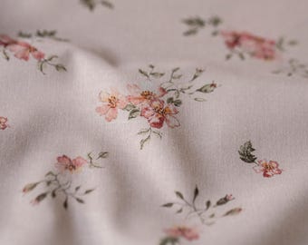 May include: A close-up of a white fabric with a delicate floral pattern. The fabric features small pink flowers with green leaves, creating a subtle and elegant design.