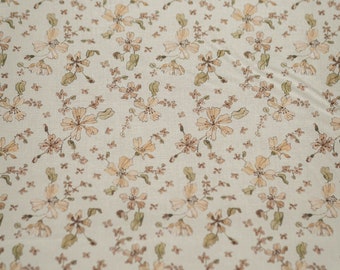 May include: A beige fabric with a delicate floral pattern. The flowers are a light brown color and are scattered randomly across the fabric.