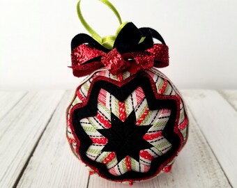 May include: A red, green, and black fabric Christmas ornament with a star design and a red and black glitter bow.