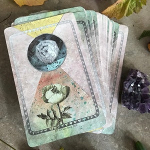 K&ouml;nnte beinhalten: Ein Tarotkarten-Deck mit einem geometrischen Design auf der Vorderseite. Die Karte zeigt eine wei&szlig;e Mohnblume und eine blaue und graue geometrische Form. Der Text "Claire Mack 2020" ist in der unteren rechten Ecke gedruckt.