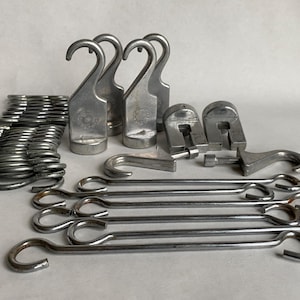 May include: A collection of various metal hardware pieces, including hooks, springs, and clasps. The items are silver-toned and appear to be made of steel or a similar metal. The hooks are of different sizes and shapes, suitable for hanging or securing items.