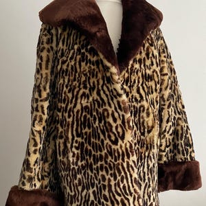 May include: A leopard print faux fur coat with a brown collar and cuffs. The coat is displayed on a mannequin. The coat is a classic style. The coat's pattern is brown and beige.