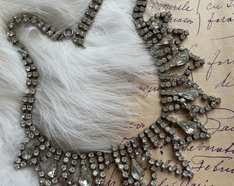 Peut inclure: Un collier en strass argenté avec un motif en forme de larme. Le collier est composé de petits strass transparents sertis dans un métal argenté. Le collier a un aspect délicat et élégant.