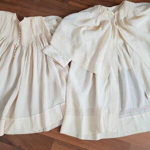 May include: Two white cotton baby dresses with delicate embroidery and lace trim. The dresses are made of a soft, lightweight fabric and have a classic, timeless design.