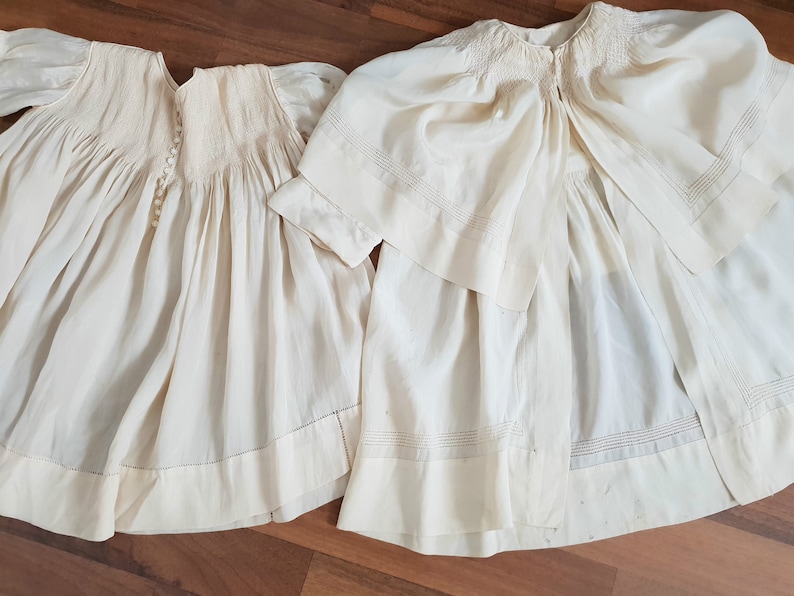 May include: Two white cotton baby dresses with delicate embroidery and lace trim. The dresses are made of a soft, lightweight fabric and have a classic, timeless design.