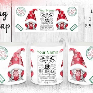 May include: White ceramic mug with a festive design. The mug features a gnome wearing a red hat with snowflake patterns. The mug wrap design includes the text "North Pole Hot Chocolate Served Here". The mug is 21.59 cm wide and 8.89 cm tall.
