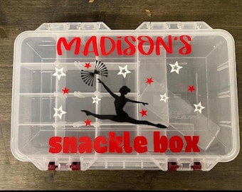 May include: A clear plastic snack box with multiple compartments. The box is decorated with red text that reads "Madison's snack box". A black silhouette of a dancer and white stars and red stars are also on the box.