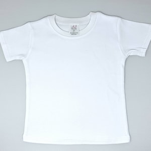 Pu&ograve; includere: Maglietta bianca a maniche corte con una piccola etichetta rosa che dice "AJ Threads 3T 100% Combed Cotton Made in China"