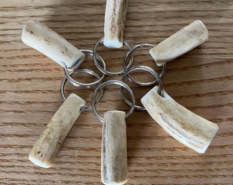 May include: Six antler keychains with silver key rings. The antler keychains are a light brown color with dark brown markings.