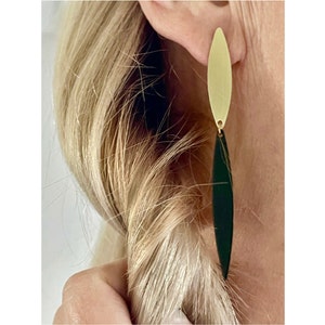 May include: Gold and black dangle earrings with a long, thin, oval shape.