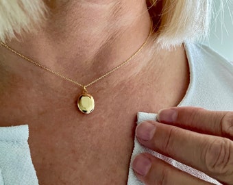 May include: A gold chain necklace with a small, round locket pendant.