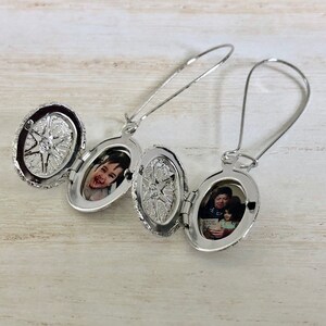 May include: A pair of silver locket earrings with a photo of a child and a photo of a man and child inside. The lockets are open and the photos are visible.